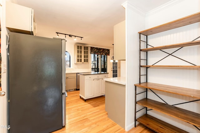 kitchen featuring light wood finished floors, ornamental molding, decorative backsplash, freestanding refrigerator, and open shelves