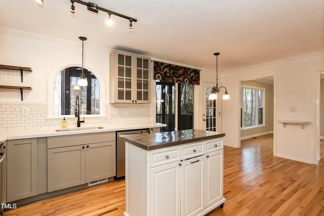 kitchen featuring light wood finished floors, open shelves, ornamental molding, a sink, and dishwasher