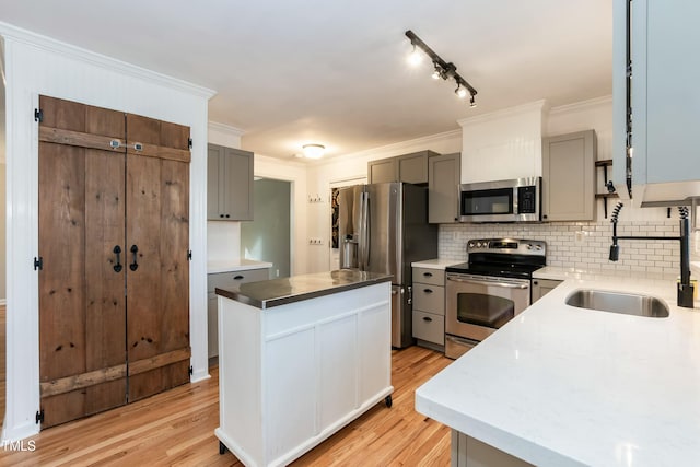 kitchen featuring gray cabinets, ornamental molding, appliances with stainless steel finishes, backsplash, and a center island