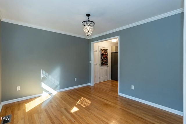 empty room featuring baseboards, wood finished floors, and a chandelier