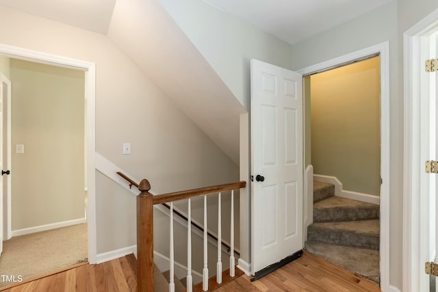 staircase with lofted ceiling, baseboards, and wood finished floors