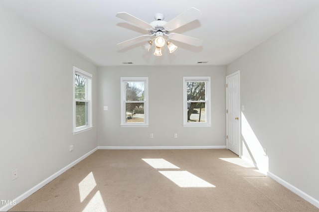 unfurnished room featuring visible vents, light colored carpet, baseboards, and ceiling fan