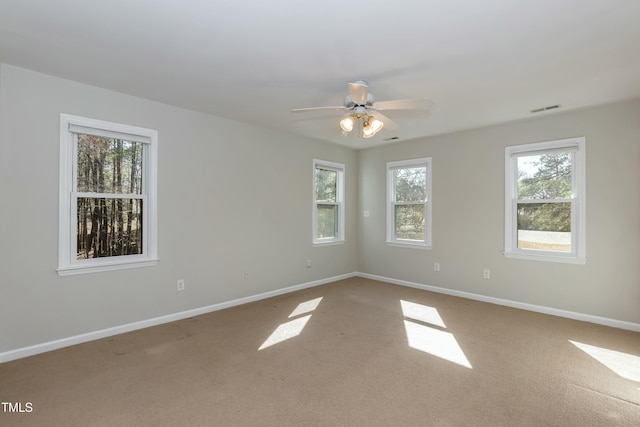 carpeted spare room with visible vents, baseboards, and a ceiling fan