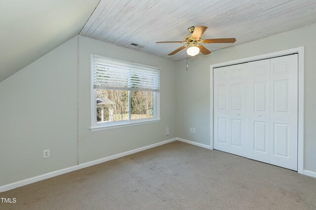 unfurnished bedroom featuring carpet, visible vents, baseboards, lofted ceiling, and a closet