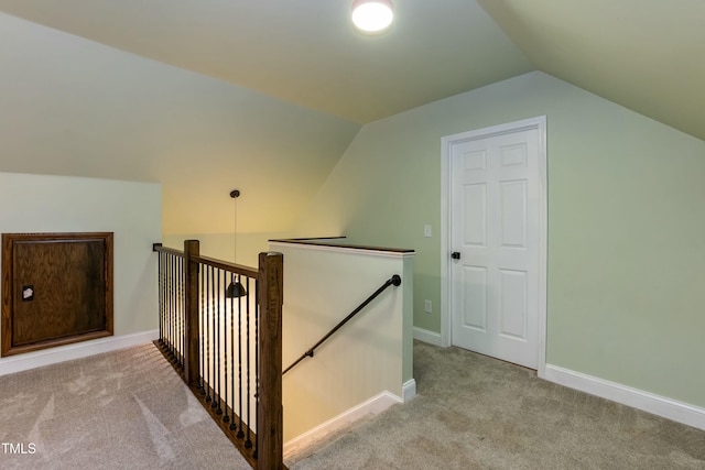 interior space featuring vaulted ceiling, an upstairs landing, baseboards, and carpet floors