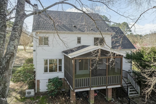 back of property with a chimney, stairway, a shingled roof, and a sunroom