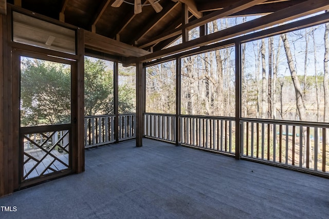 unfurnished sunroom featuring lofted ceiling with beams and a ceiling fan