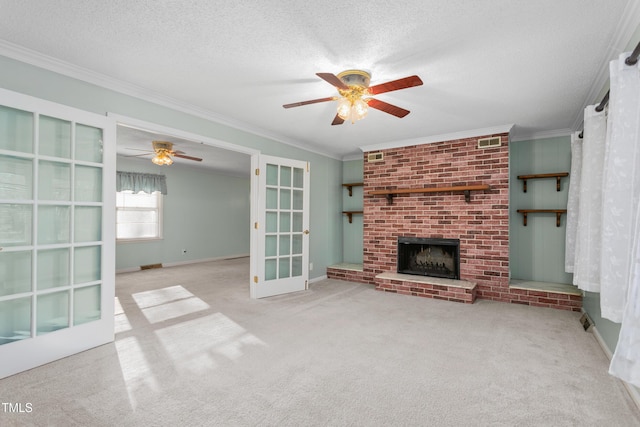 unfurnished living room featuring a ceiling fan, carpet floors, ornamental molding, a textured ceiling, and a brick fireplace