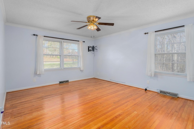 empty room featuring light wood-style floors, crown molding, a ceiling fan, and visible vents