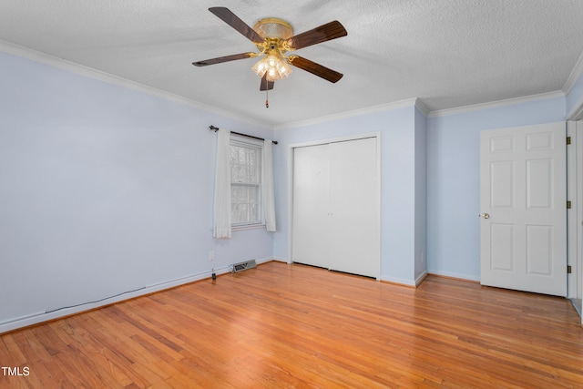 unfurnished bedroom featuring visible vents, a closet, a textured ceiling, crown molding, and light wood-type flooring