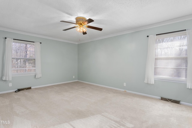 carpeted empty room featuring a wealth of natural light, visible vents, ceiling fan, and ornamental molding