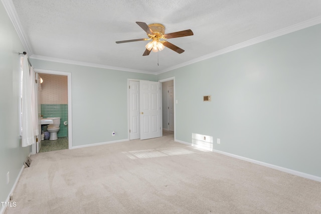 unfurnished bedroom featuring baseboards, ensuite bath, ornamental molding, and carpet flooring