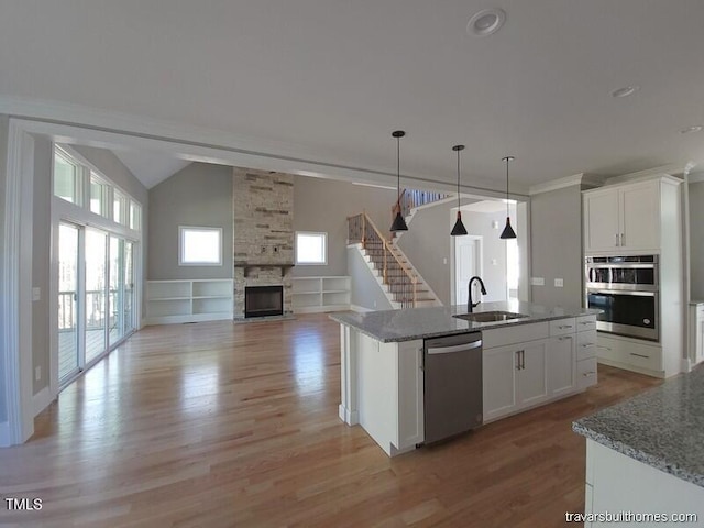 kitchen with a wealth of natural light, a fireplace, appliances with stainless steel finishes, and a sink