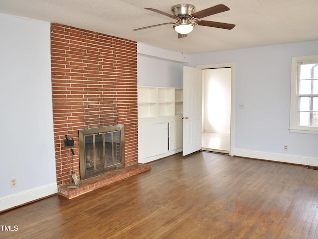 unfurnished living room with dark wood-type flooring, baseboards, ceiling fan, a fireplace, and a textured ceiling