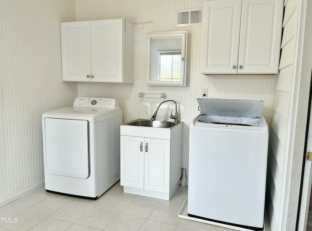 washroom featuring visible vents, light tile patterned floors, washer and dryer, cabinet space, and a sink