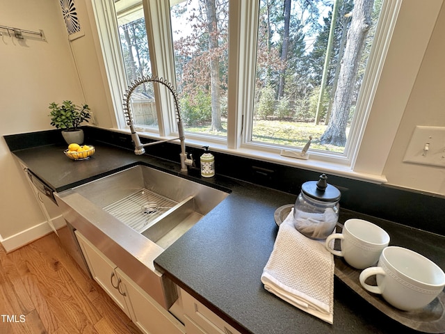 room details with dark countertops, white cabinetry, light wood-style floors, and a sink