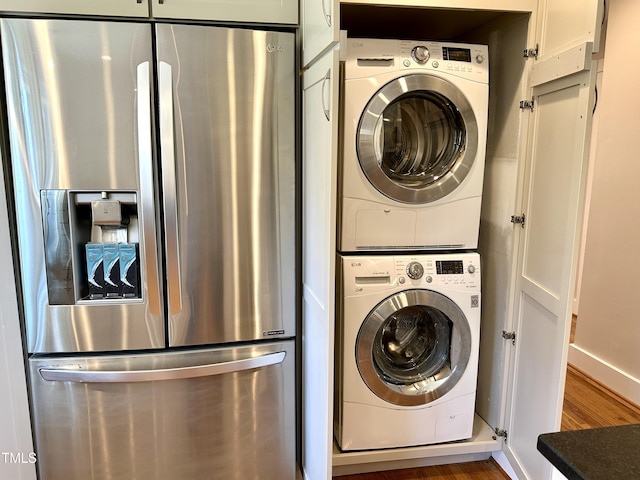 washroom featuring laundry area, wood finished floors, and stacked washing maching and dryer