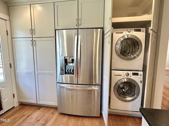 laundry room featuring stacked washer and clothes dryer, laundry area, and light wood finished floors