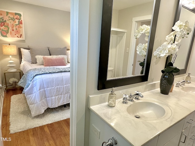 bathroom with a sink, connected bathroom, wood finished floors, and double vanity