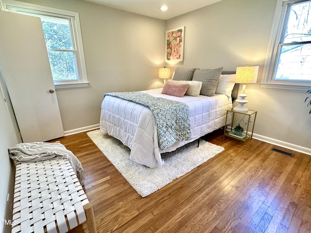 bedroom with visible vents, baseboards, and wood finished floors