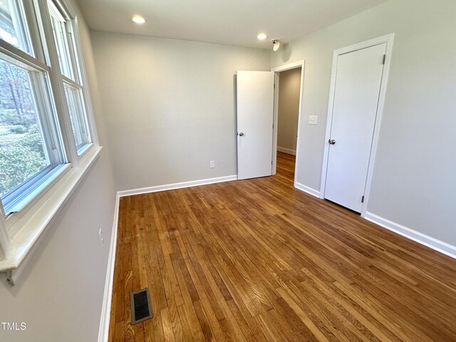 spare room with recessed lighting, wood finished floors, visible vents, and baseboards