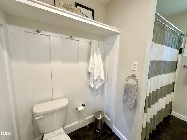 bathroom featuring baseboards, toilet, and a shower with curtain