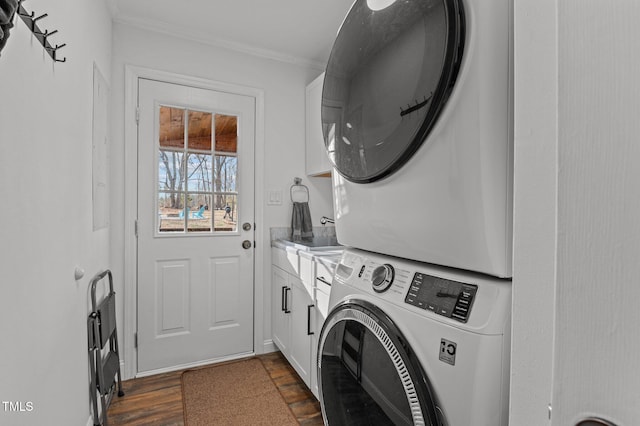 washroom featuring dark wood-style floors, cabinet space, stacked washer and clothes dryer, and ornamental molding