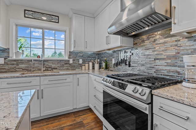 kitchen with a sink, dark wood finished floors, white cabinets, wall chimney range hood, and stainless steel range with gas stovetop