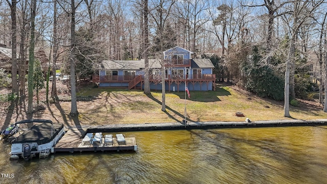 dock area with stairs, a deck with water view, and a lawn