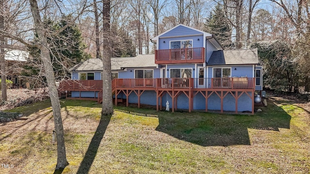 back of house with a shingled roof, a balcony, a lawn, and a wooden deck