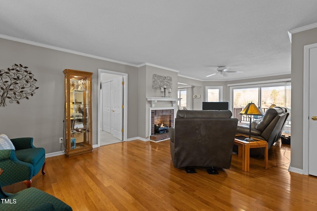 living room featuring baseboards, a brick fireplace, crown molding, and light wood finished floors