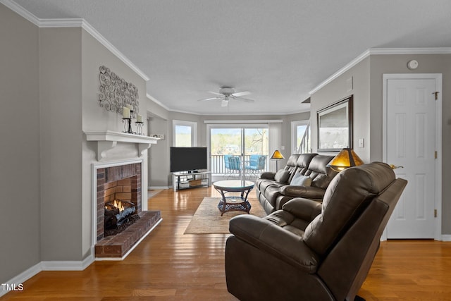 living room with ornamental molding, a fireplace, baseboards, and wood finished floors