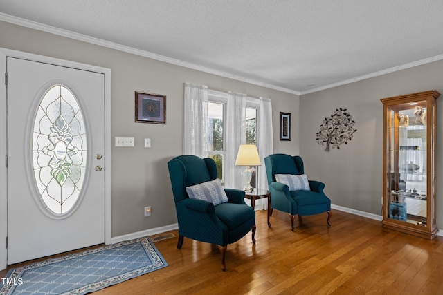 entrance foyer featuring visible vents, crown molding, baseboards, light wood-type flooring, and a textured ceiling