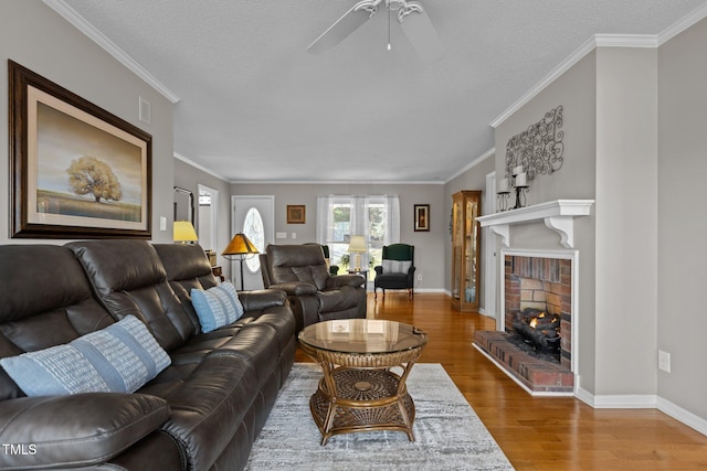 living room with wood finished floors, crown molding, a fireplace, and baseboards