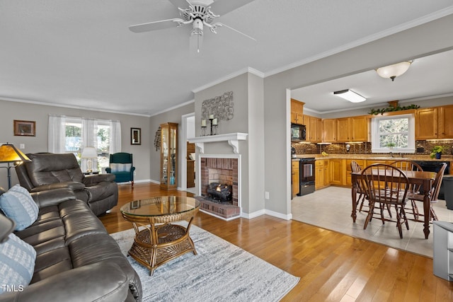 living room featuring baseboards, a fireplace, crown molding, and light wood finished floors