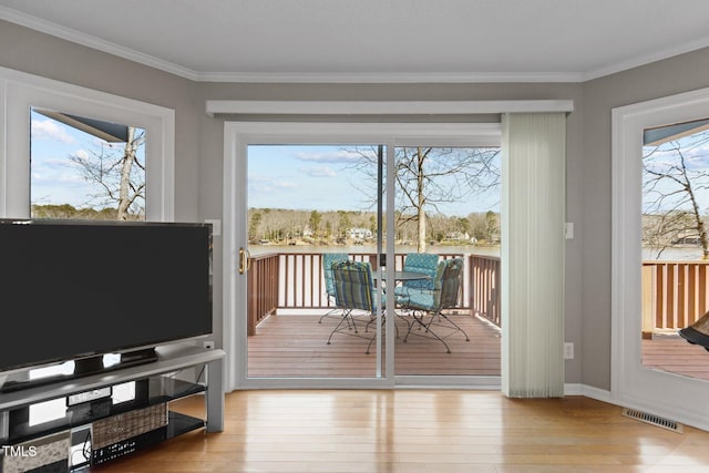 entryway with crown molding, wood-type flooring, visible vents, and a wealth of natural light