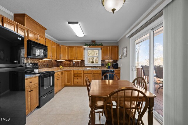 kitchen with light tile patterned floors, ornamental molding, decorative backsplash, black appliances, and a sink