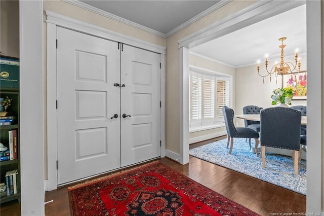 foyer featuring an inviting chandelier, dark wood-style flooring, and ornamental molding