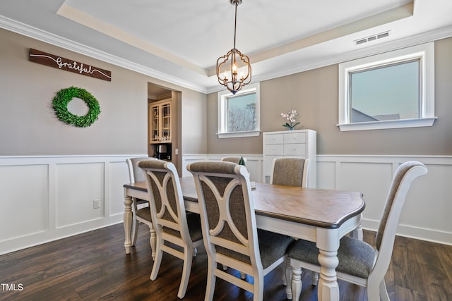 dining area featuring an inviting chandelier, a tray ceiling, dark wood-style floors, and visible vents