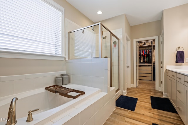 bathroom with a walk in closet, vanity, a bath, and a shower stall