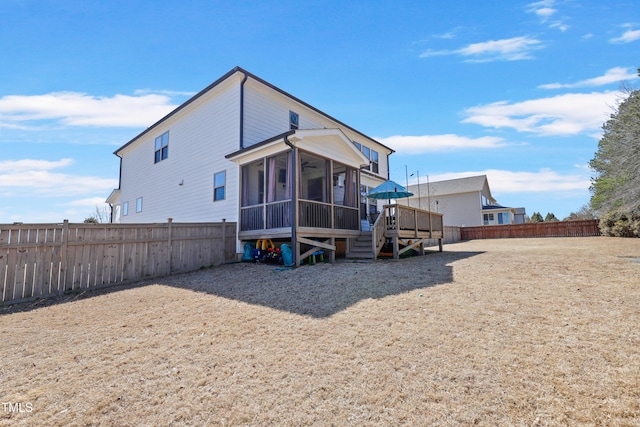 rear view of house featuring a fenced backyard and a sunroom