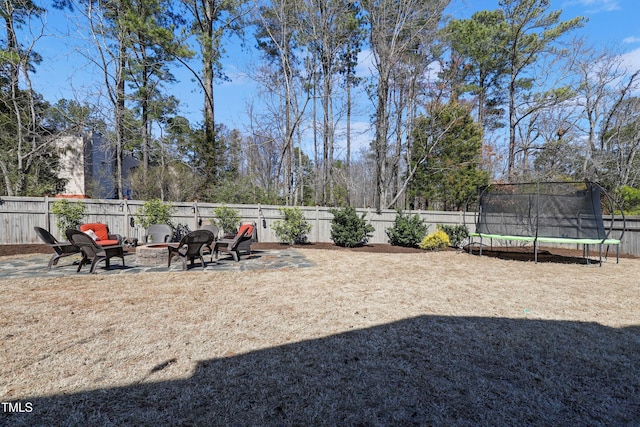 view of yard featuring a fenced backyard, a fire pit, and a trampoline