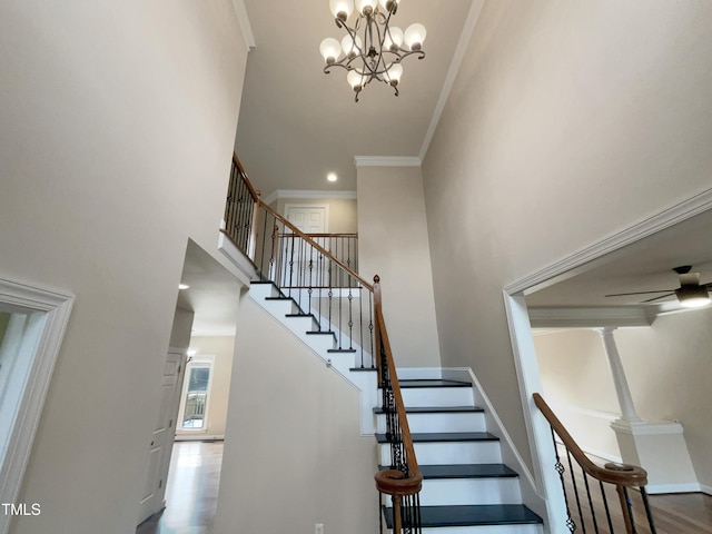 stairs with wood finished floors, baseboards, a towering ceiling, and crown molding