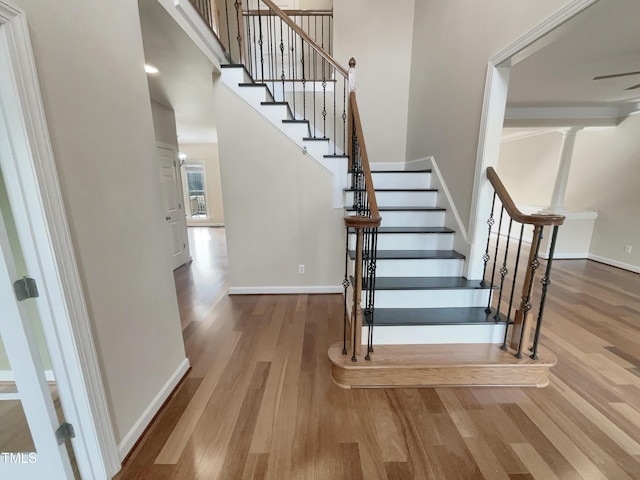 stairs featuring baseboards, wood finished floors, and a towering ceiling