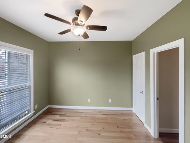 unfurnished room with a ceiling fan, light wood-type flooring, and baseboards