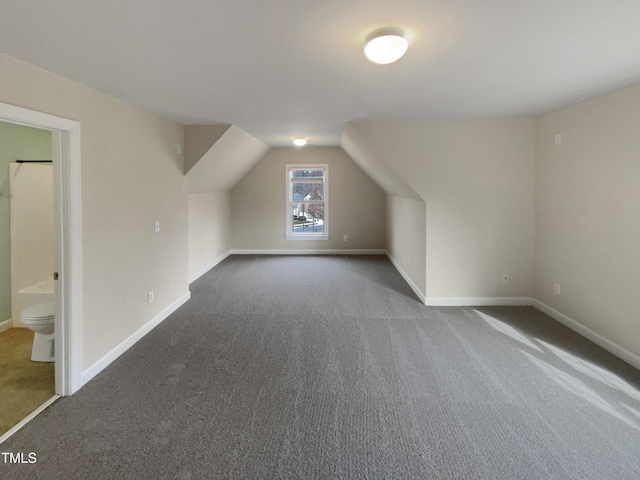 additional living space with lofted ceiling, baseboards, and dark colored carpet