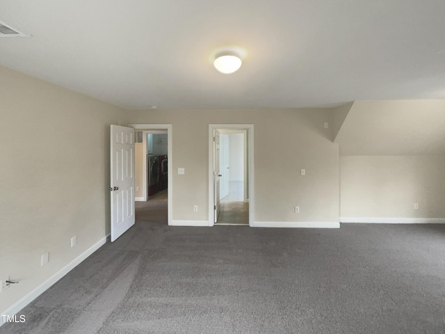 spare room with dark colored carpet, visible vents, baseboards, and washer / dryer