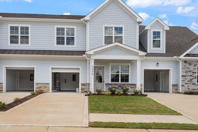 view of front of house with stone siding, driveway, metal roof, and a standing seam roof