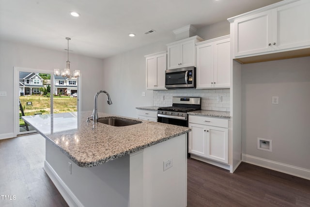 kitchen with a kitchen island with sink, a sink, stainless steel appliances, white cabinetry, and backsplash