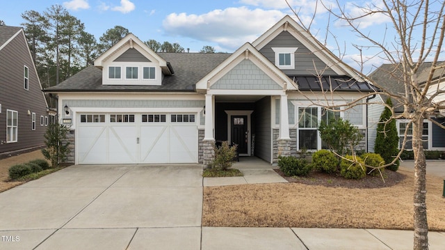 craftsman-style house with concrete driveway, an attached garage, stone siding, and roof with shingles